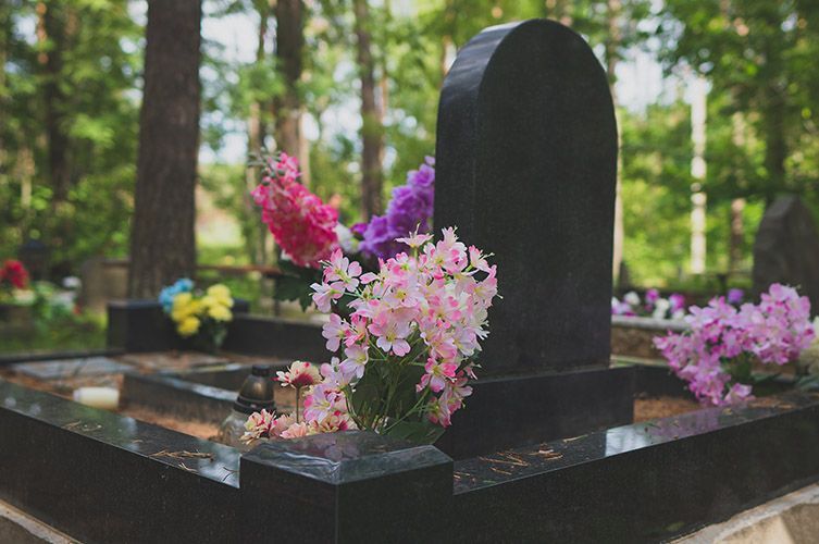A grave with flowers on it in a cemetery.