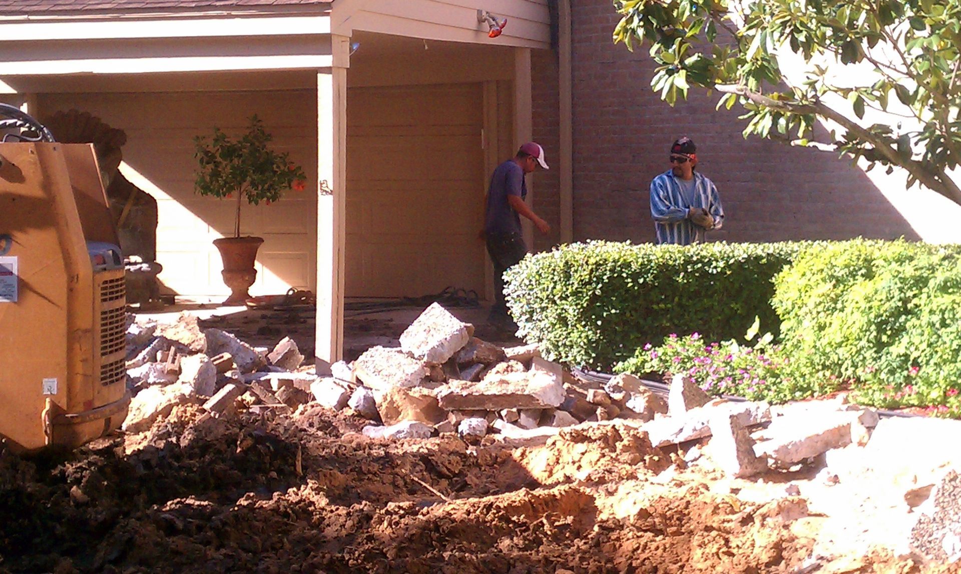 Exterior view of a beige metal industrial building with a ramp, blue sky, and a wet parking lot.