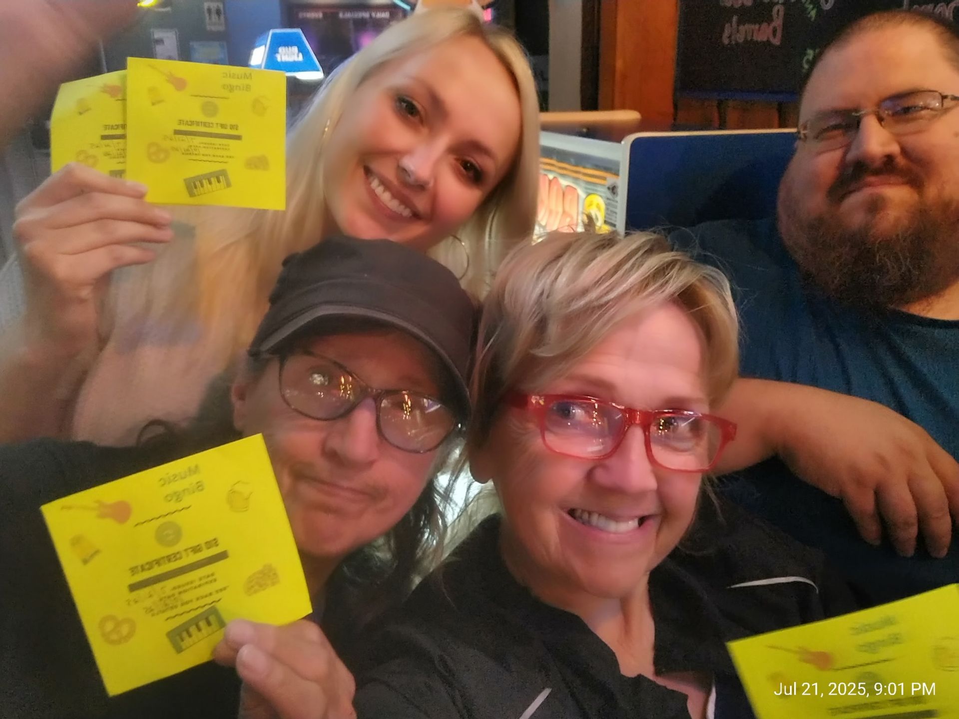 Four people smiling and holding yellow tickets indoors.