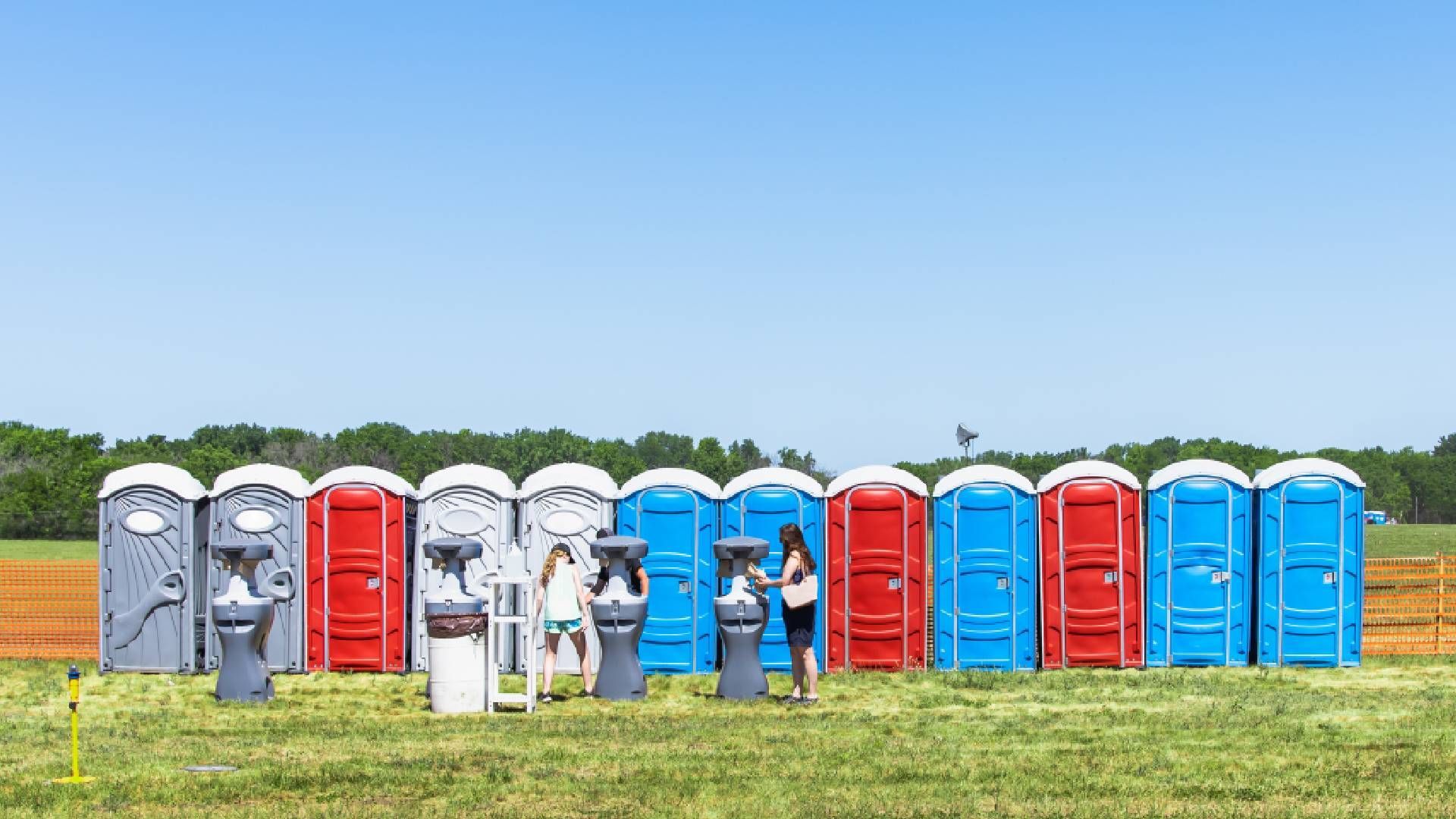 Attendees at an outdoor event using portable washrooms and handwash stations near Lexington, Kentuck