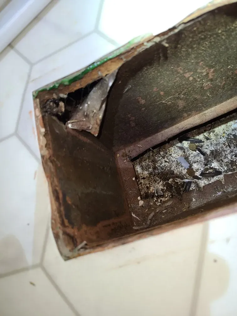 A piece of metal is sitting on a tiled floor.