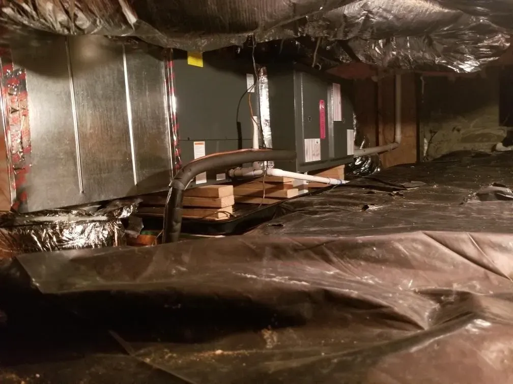 A very dark basement with a lot of plastic on the floor.