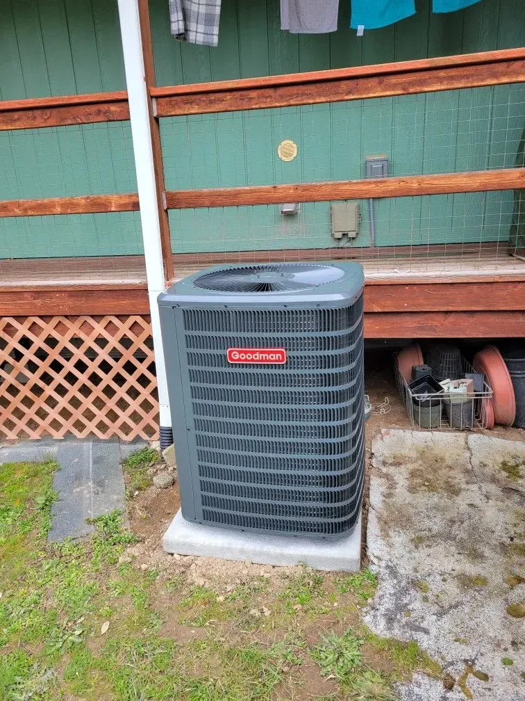 An air conditioner is sitting on the ground in front of a house.