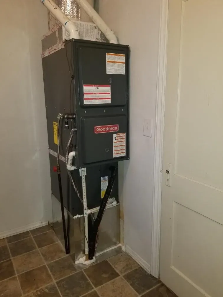 A furnace is sitting in a room next to a door.