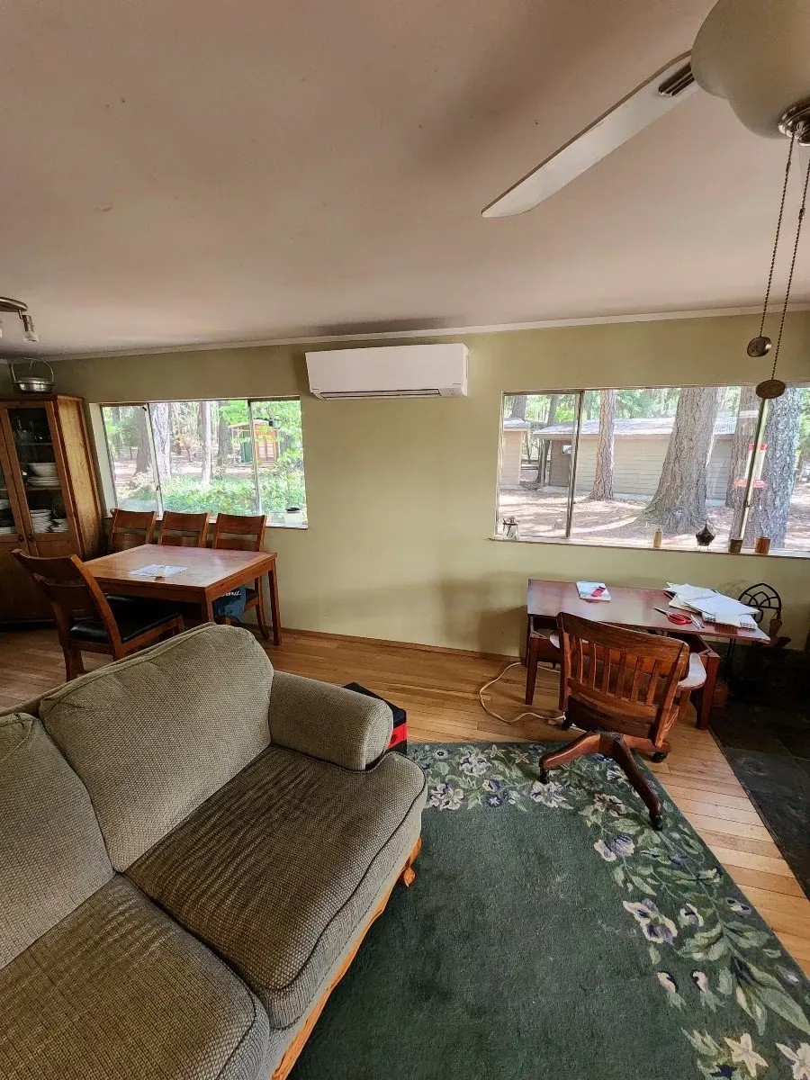 A living room with a couch , table , chairs and a ceiling fan.