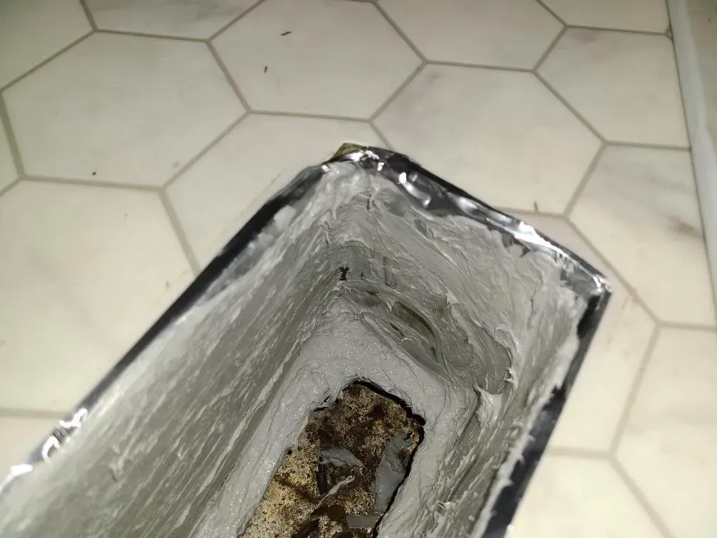 A piece of aluminum foil is sitting on a tiled floor