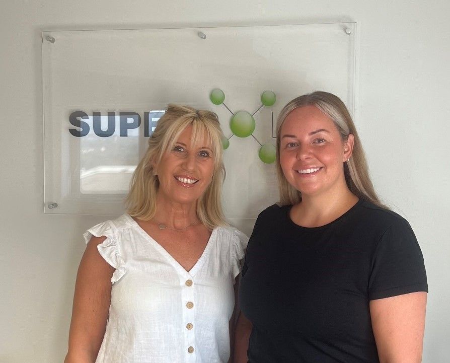 two women are standing next to each other in front of a sign that says supe .