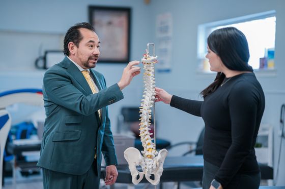 Chiropractor explaining a procedure with a spine model