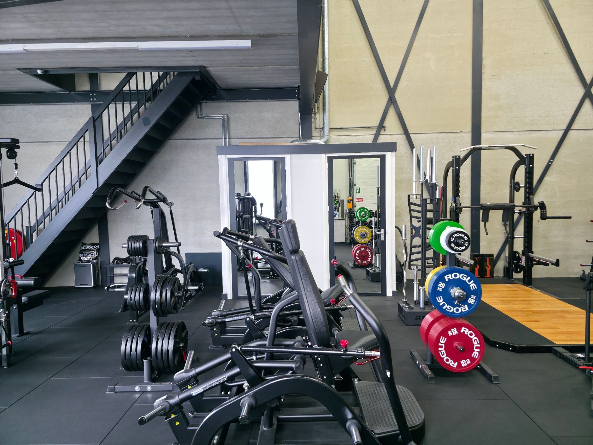 Een sportschool vol met fitnessapparatuur en een trap.