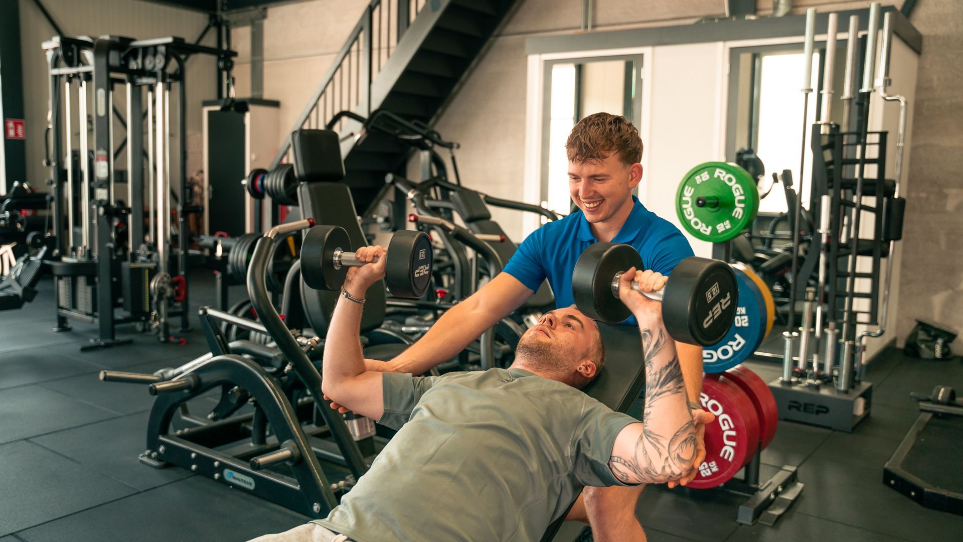 Een man tilt halters op een bankje in een sportschool.