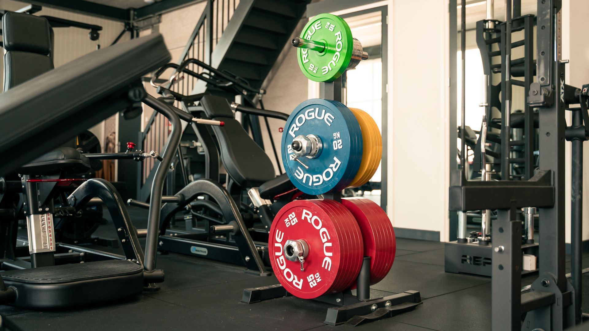 Een sportschool vol met fitnessapparatuur en gewichtsschijven.