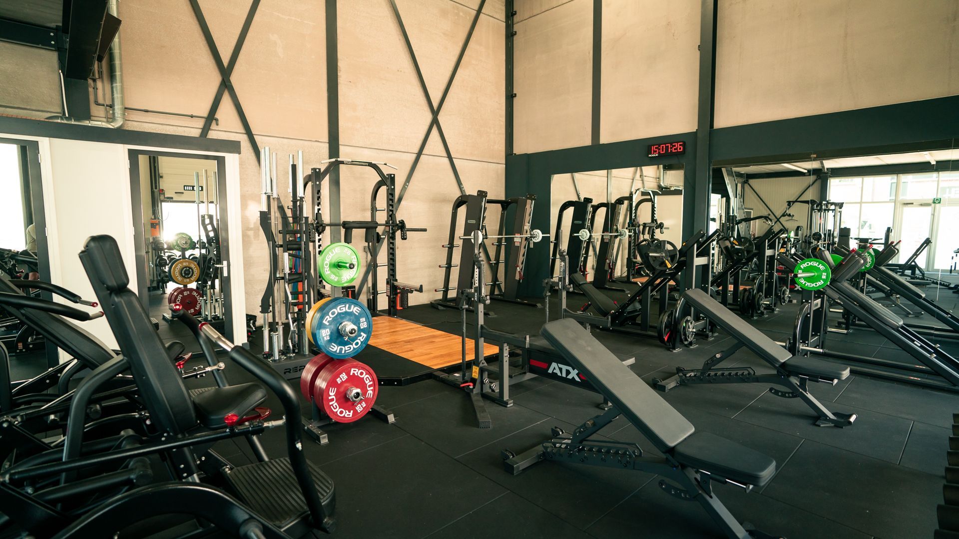Een sportschool vol met fitnessapparatuur en een grote spiegel.
