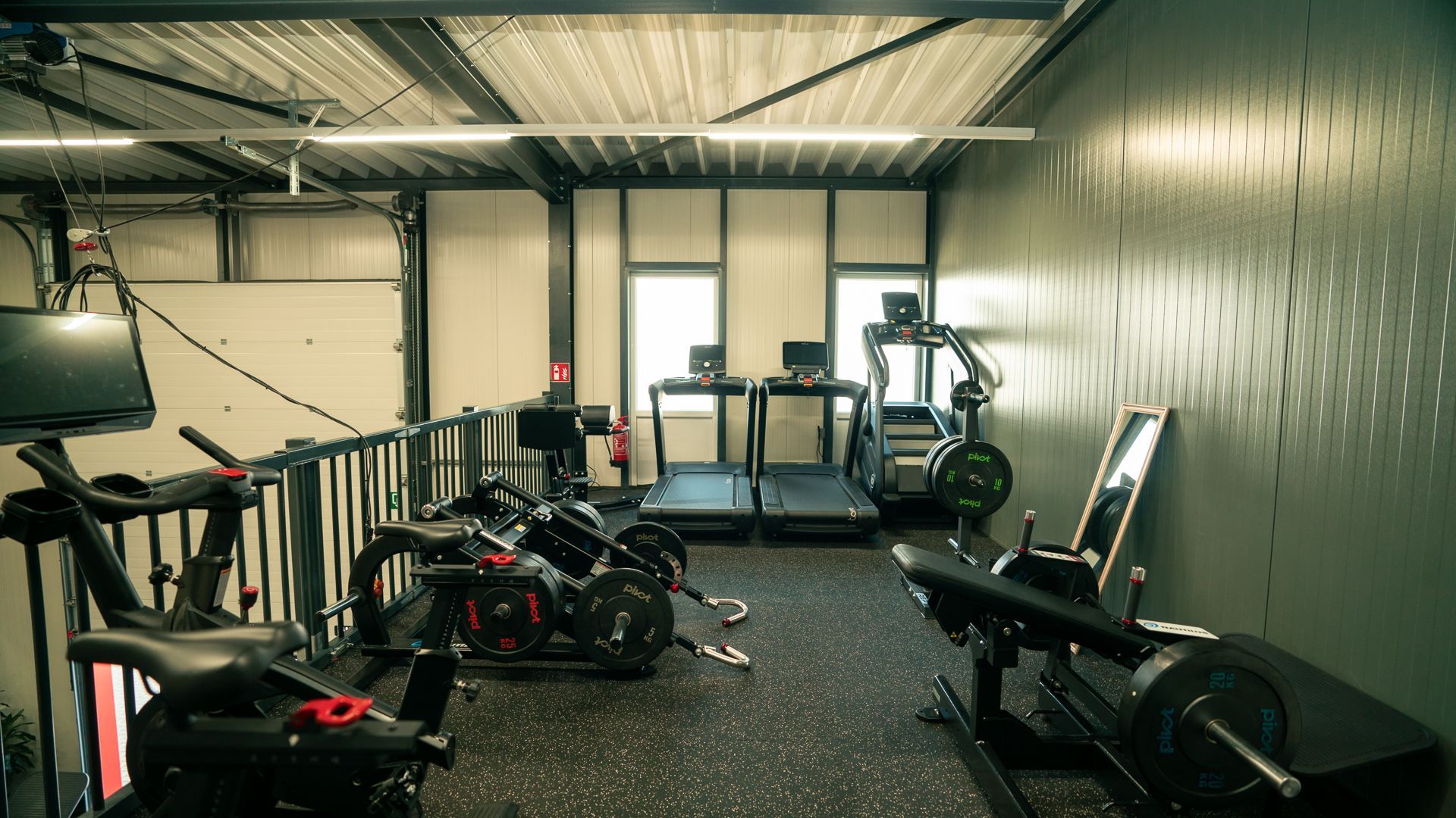 Een sportschool vol met fitnessapparatuur en een loopband.