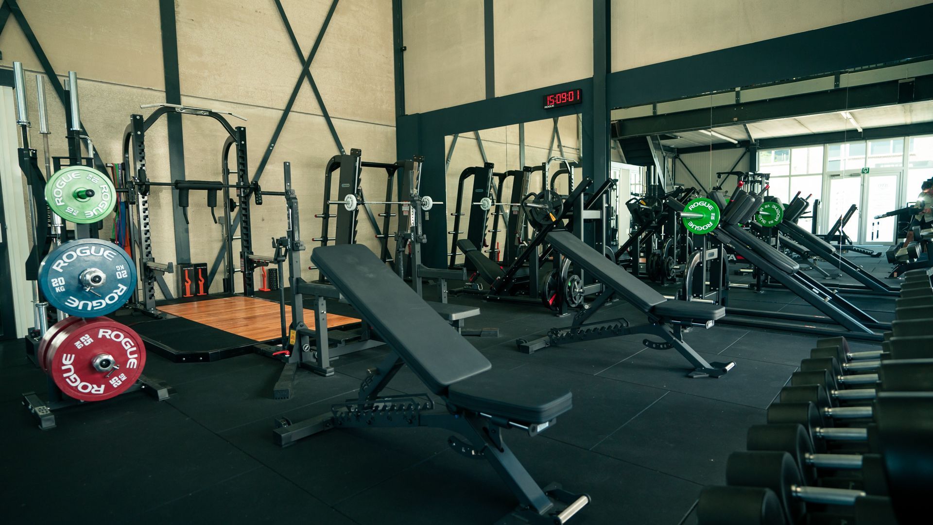 Een sportschool vol met fitnessapparatuur en halters.