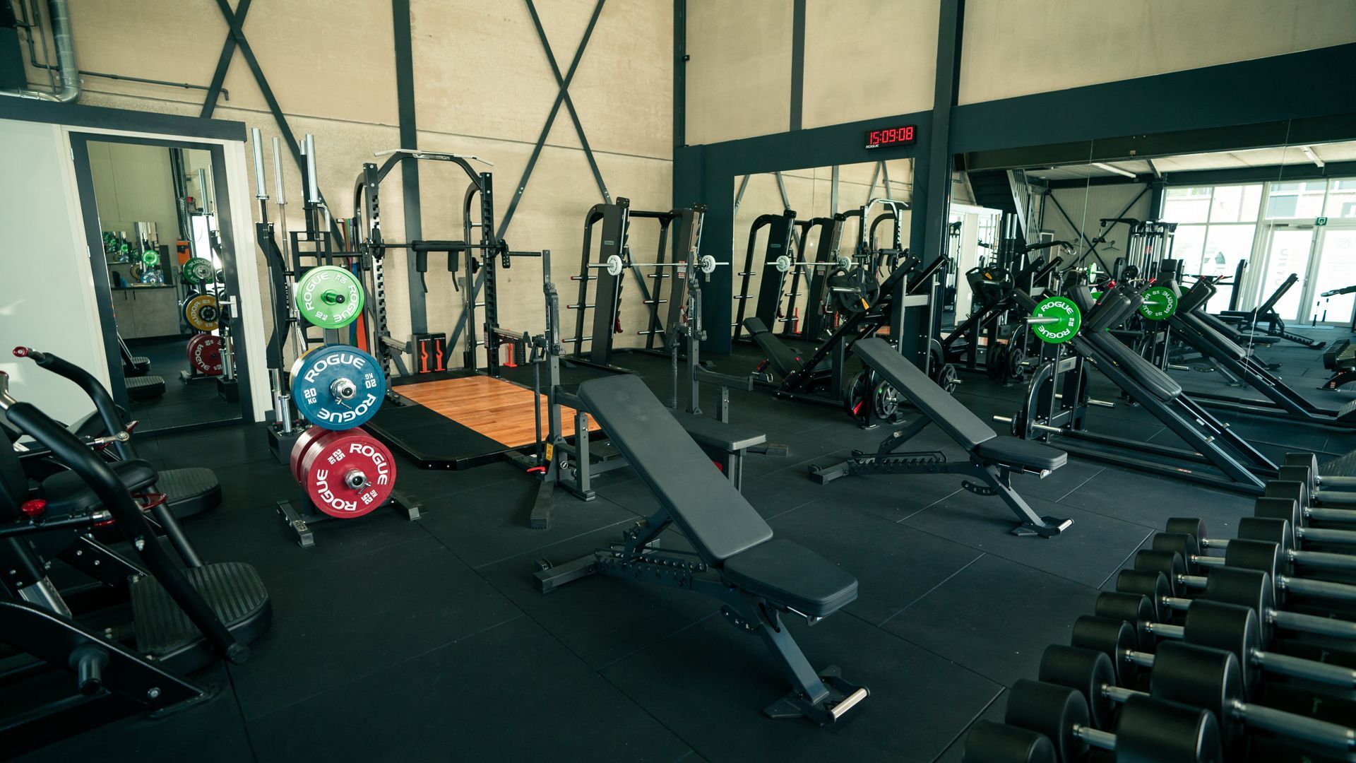 Een sportschool vol met fitnessapparatuur en halters.