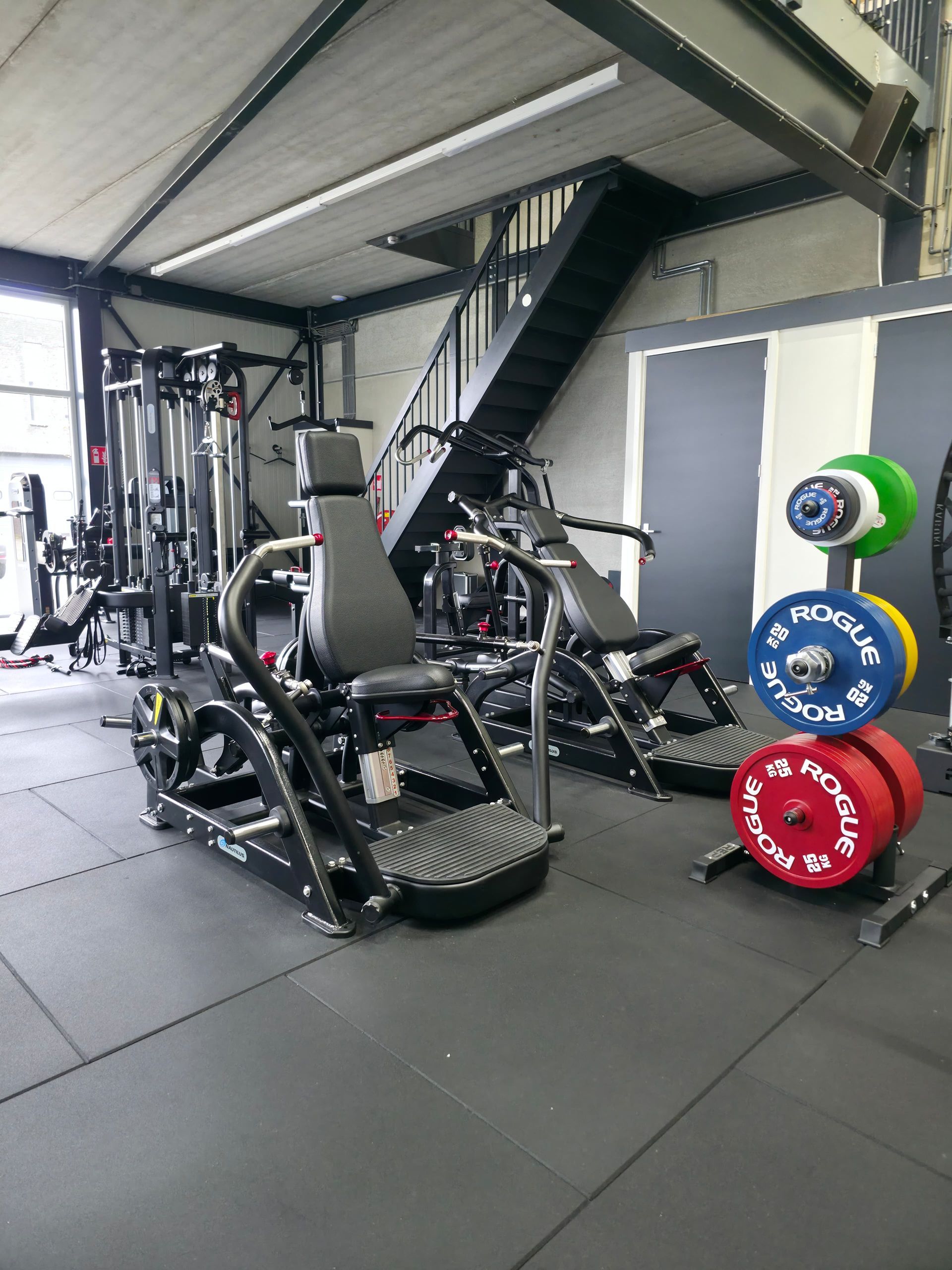 Een sportschool vol met fitnessapparatuur en gewichten.