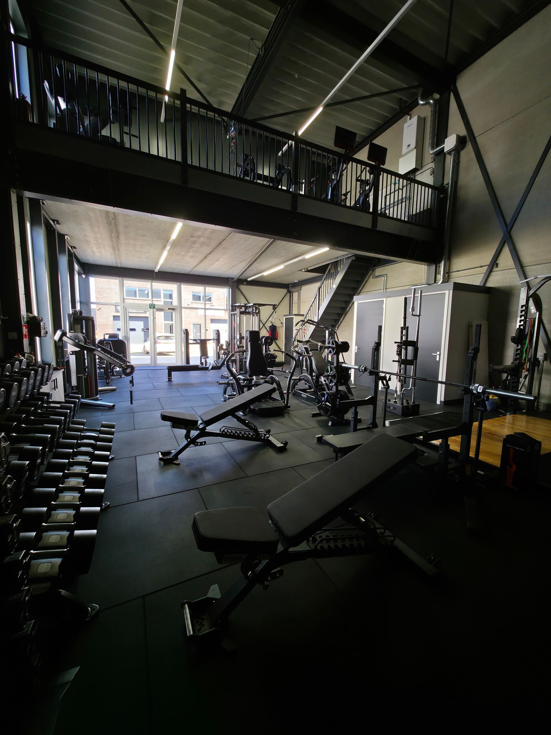 Een sportschool met balkon en veel fitnessapparatuur