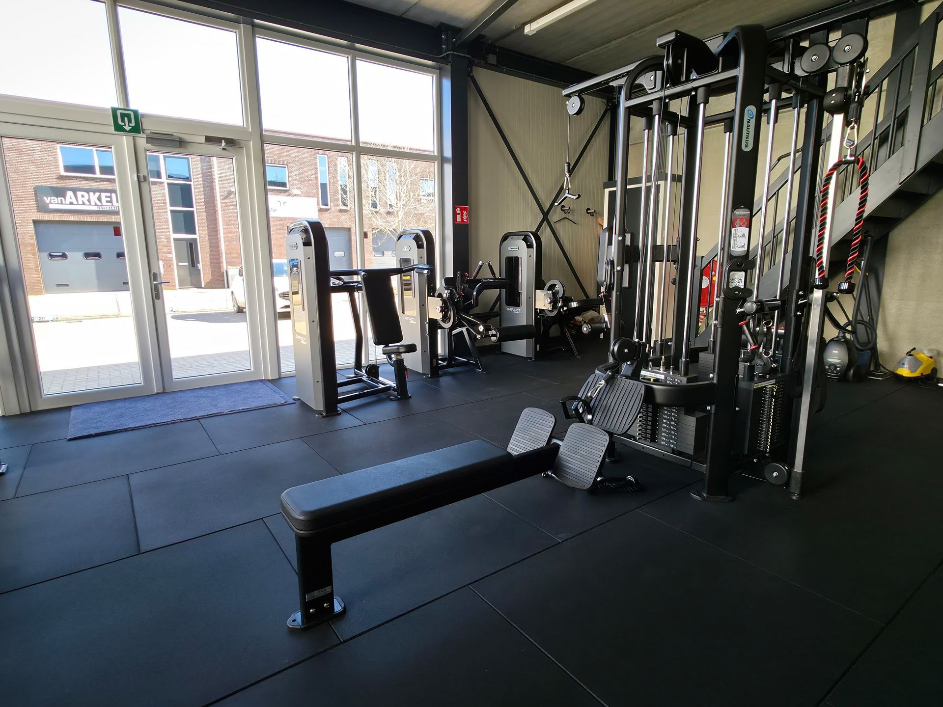 Een sportschool met veel fitnessapparatuur en een bank.