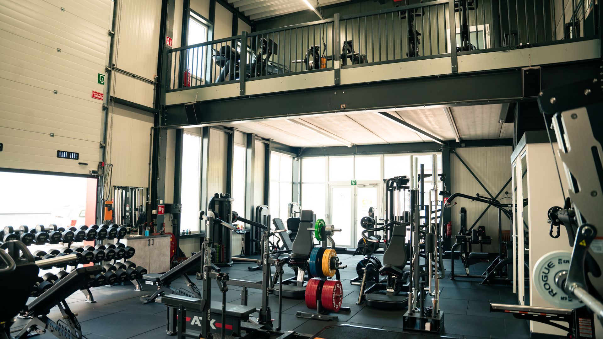 Een sportschool met veel fitnessapparatuur en een balkon.