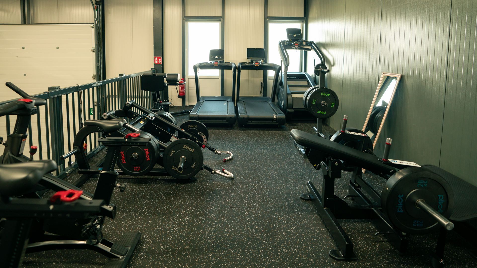 Een sportschool vol met fitnessapparatuur en een loopband.