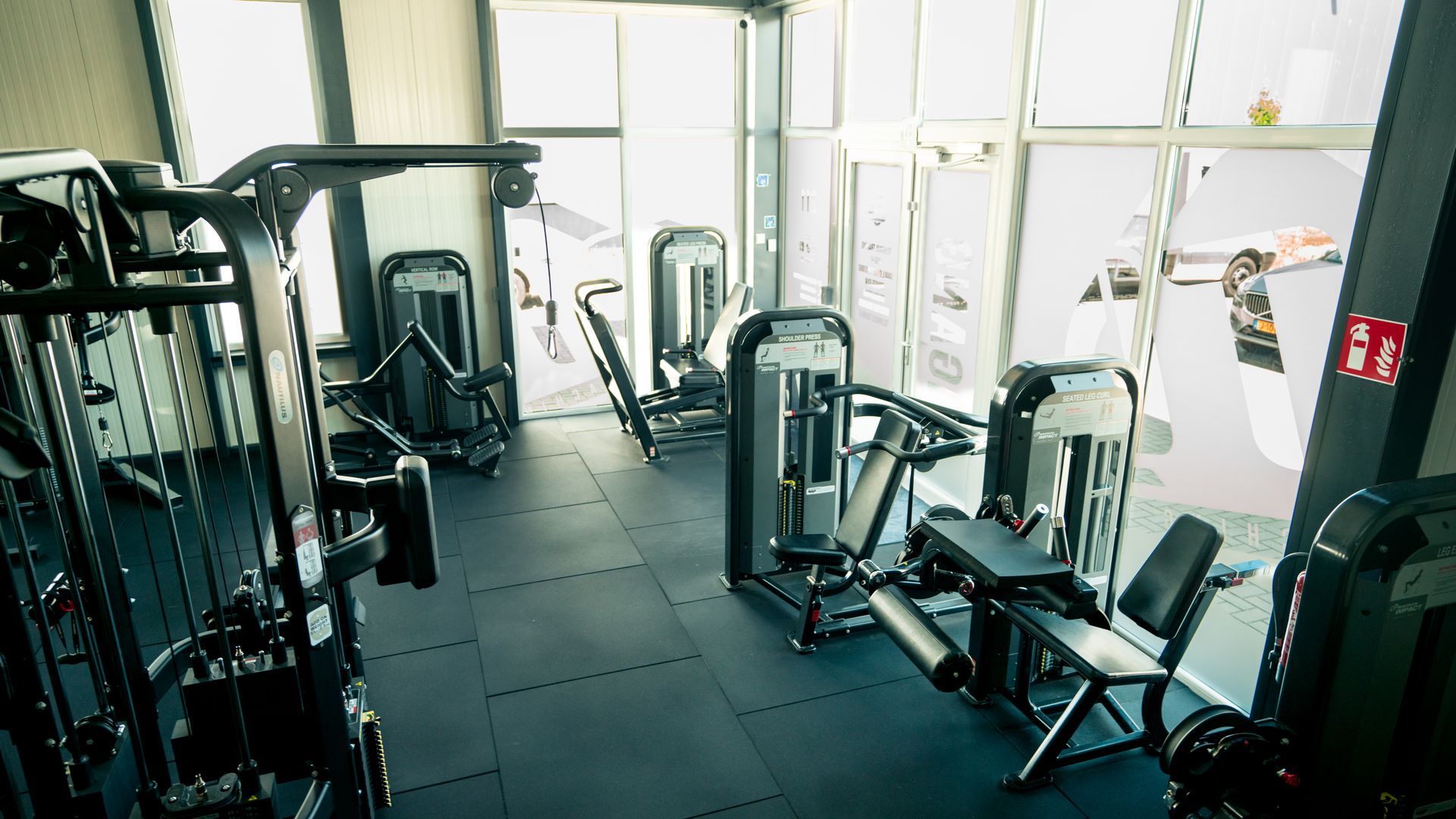 Een sportschool vol met fitnessapparatuur en een groot raam.