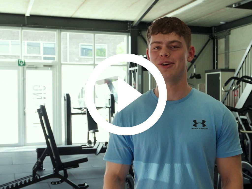 Een man in een blauw Under Armour-shirt staat in een sportschool.