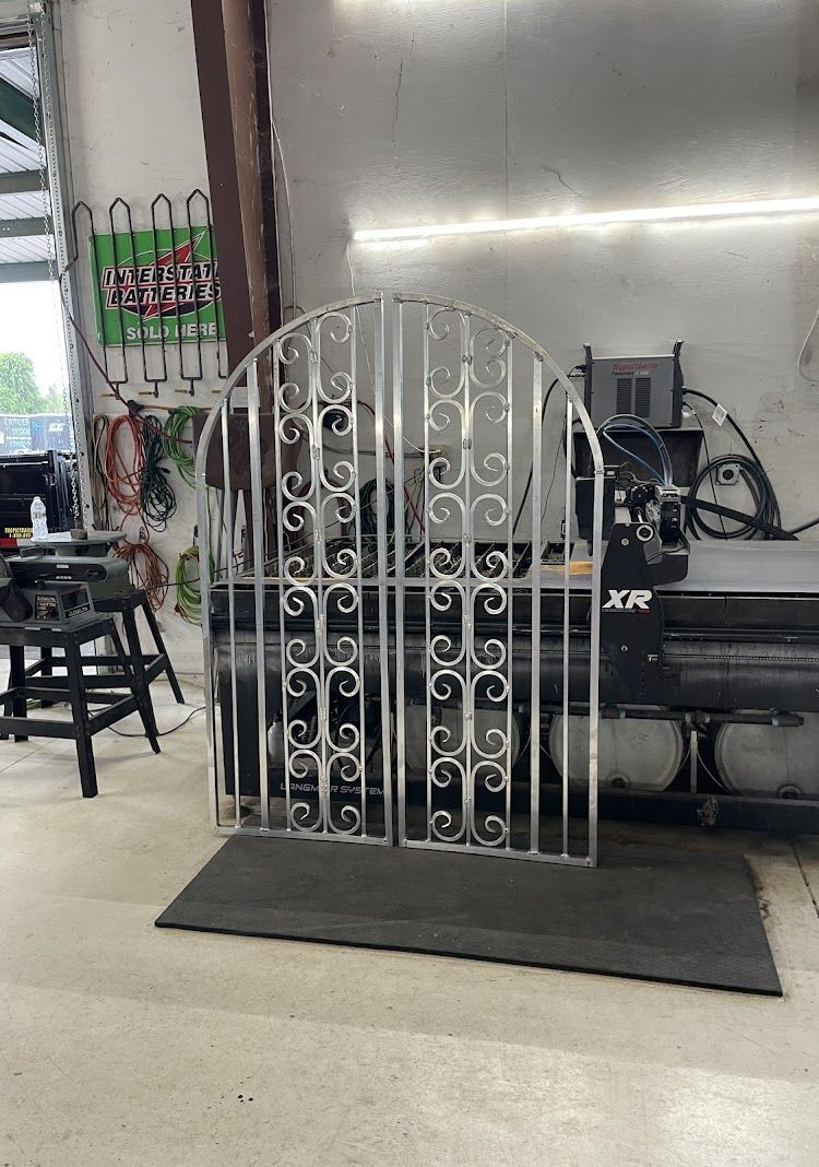 Metal gate with scrollwork design in a workshop setting.