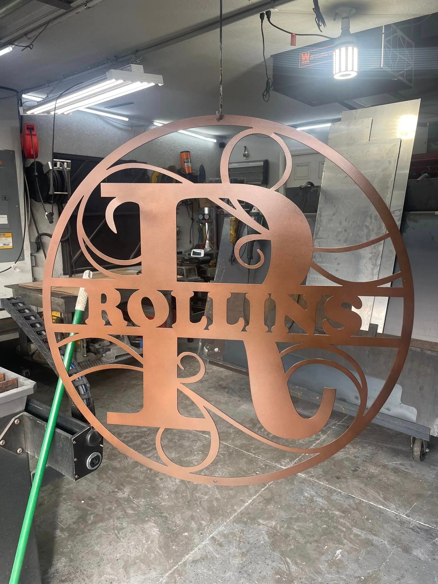 Copper-colored metal family name sign with a large letter 