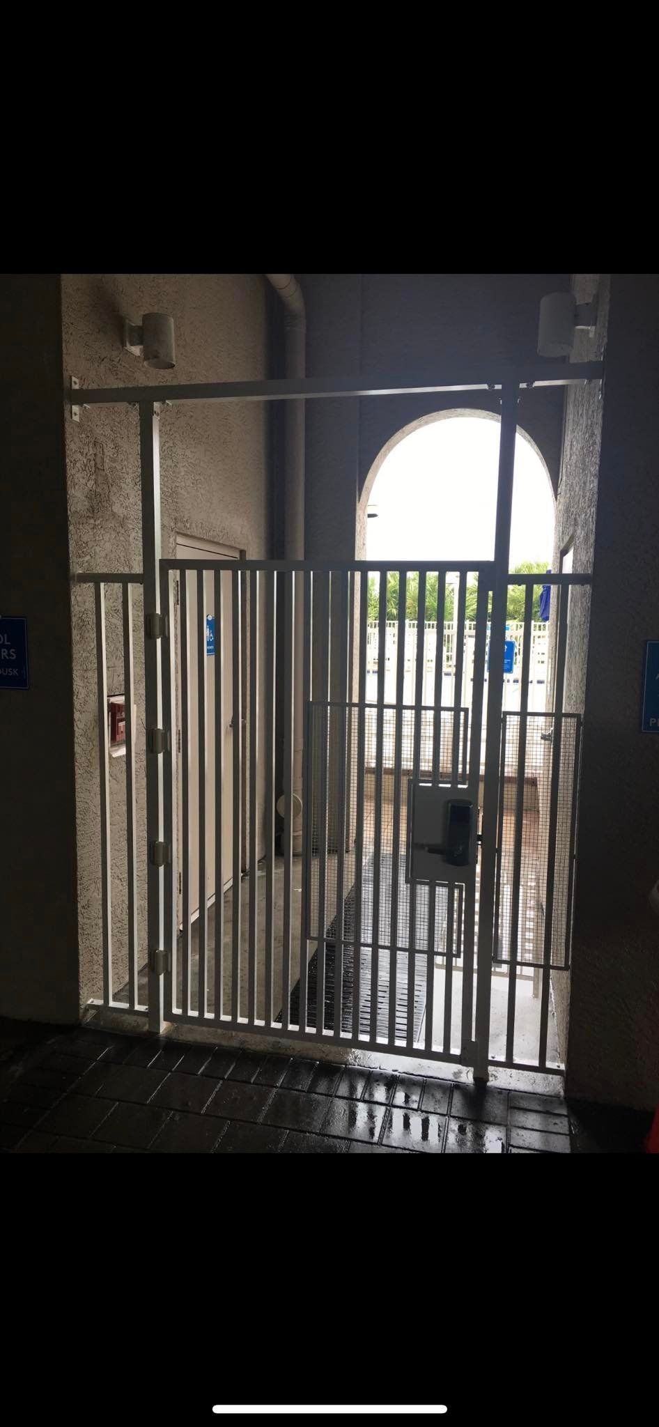 Metal gate inside an archway; looking out to a courtyard.