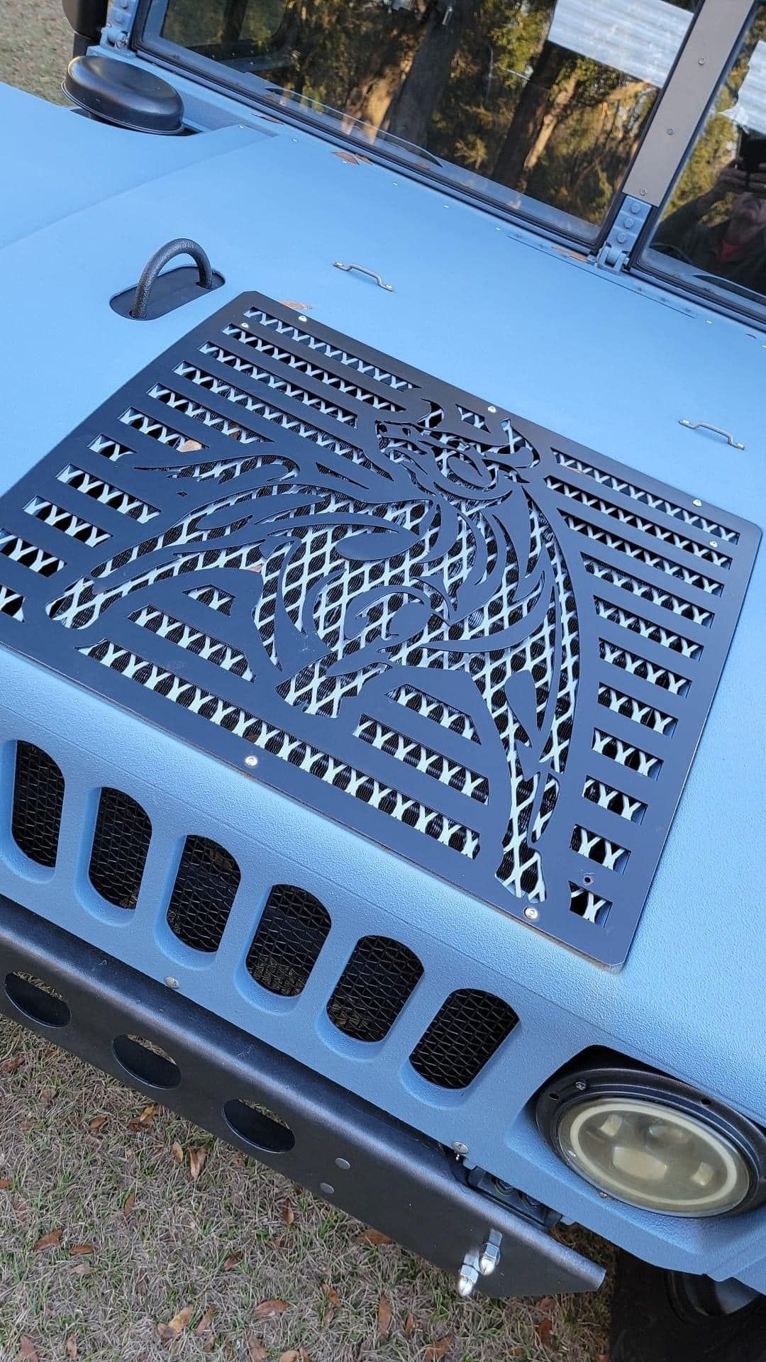 Blue Humvee with a decorative black grille on its hood.