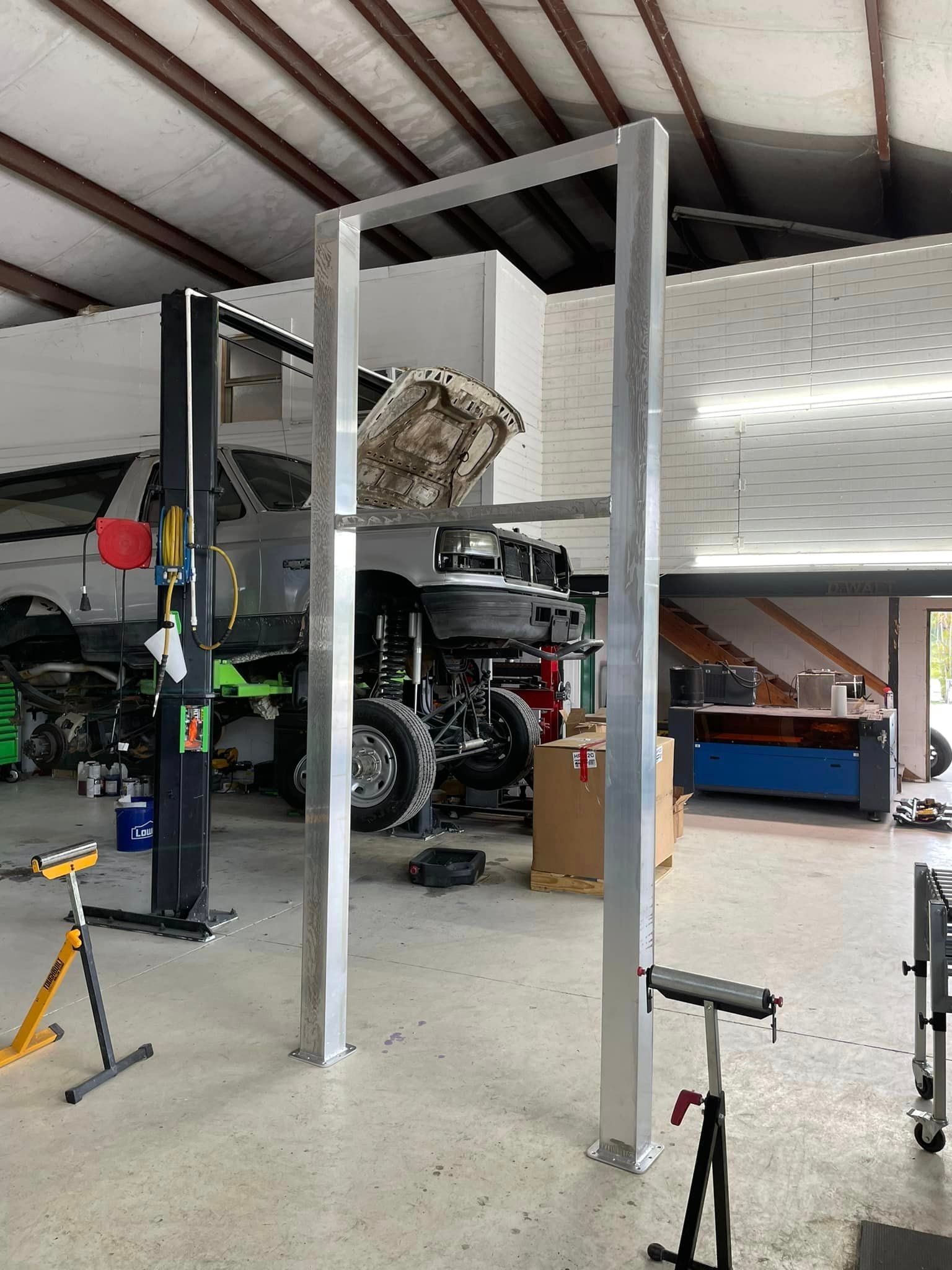 Aluminum frame structure in a garage; a truck on a lift in the background.