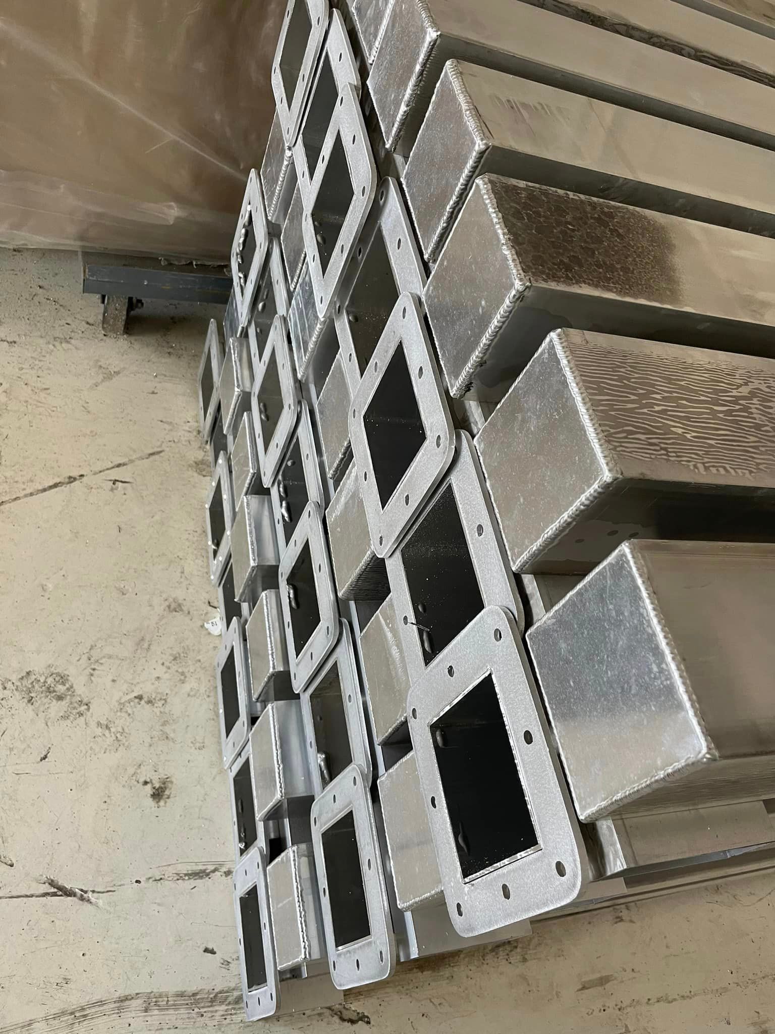 Stack of rectangular metal pieces with openings and mounting holes.