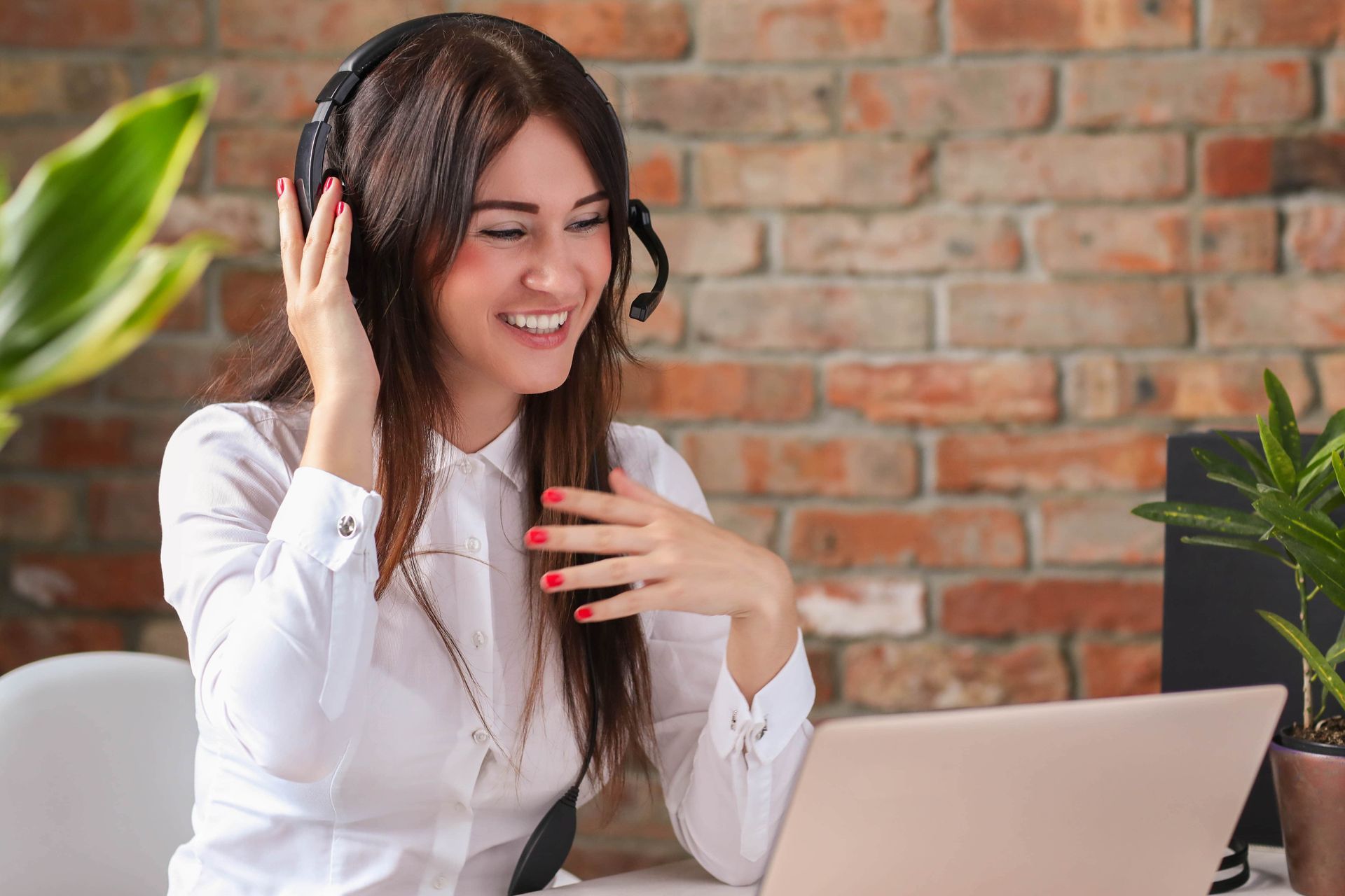 A woman wearing headphones is sitting in front of a laptop computer.