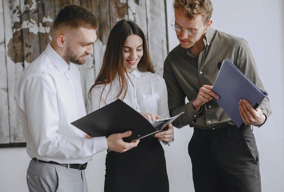 A group of people are standing next to each other looking at a folder.