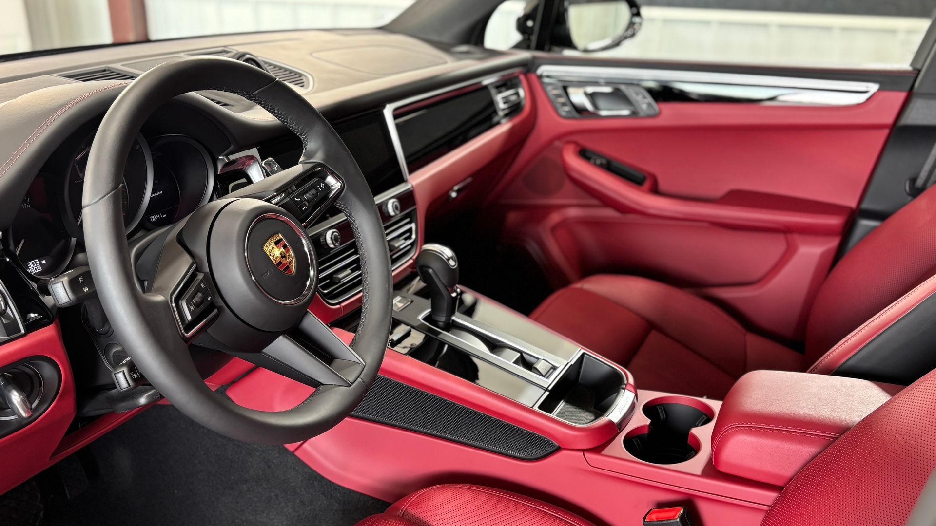 Hand holding a black paint thickness gauge on red car surface, displaying 10.56.
