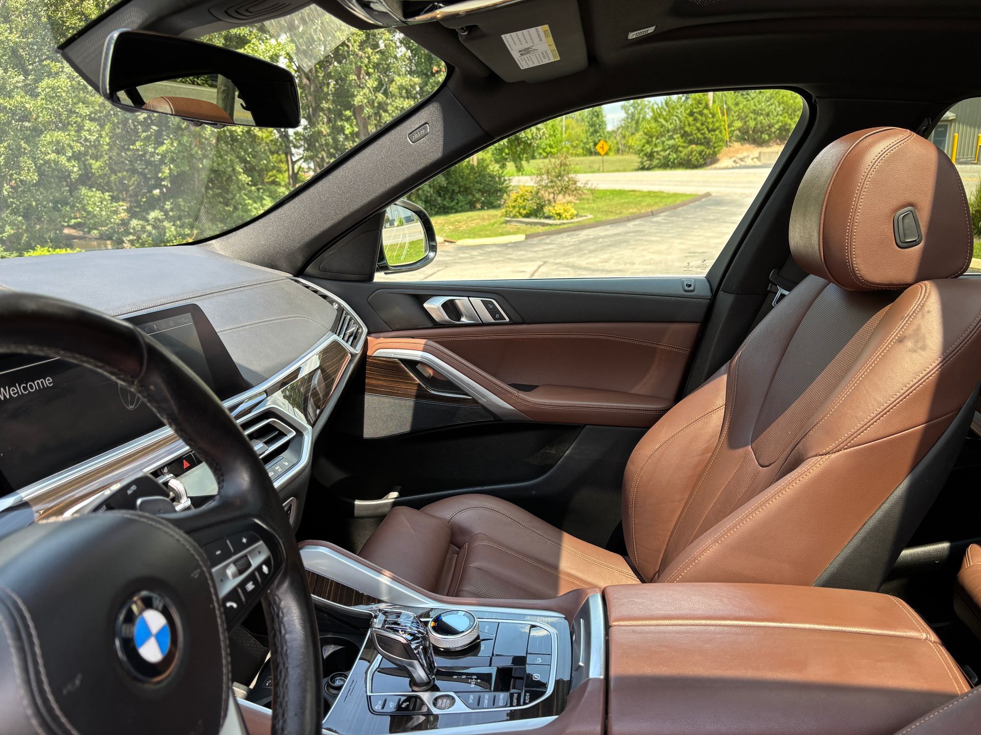 Interior of a brown leather BMW car, with the steering wheel, dashboard, and front seat visible.