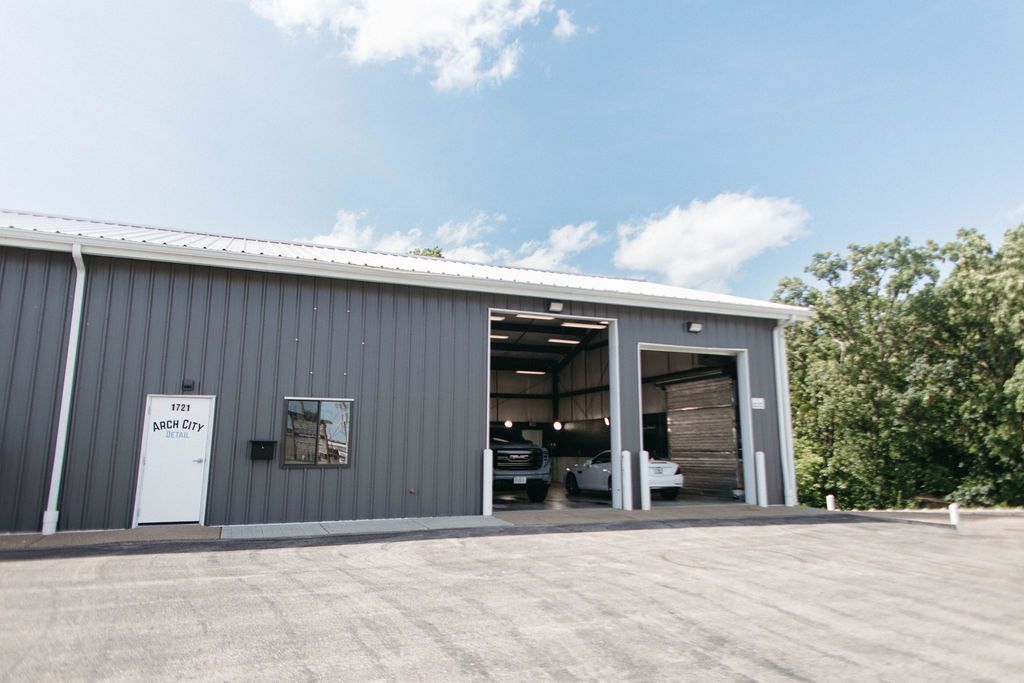 Gray building with open garage doors; cars inside. Blue sky.