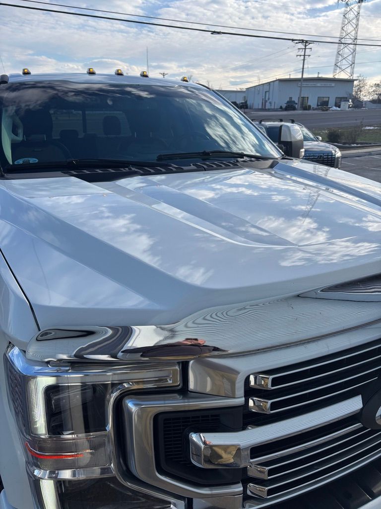 White truck with chrome grille and lights; blue sky and buildings in background.
