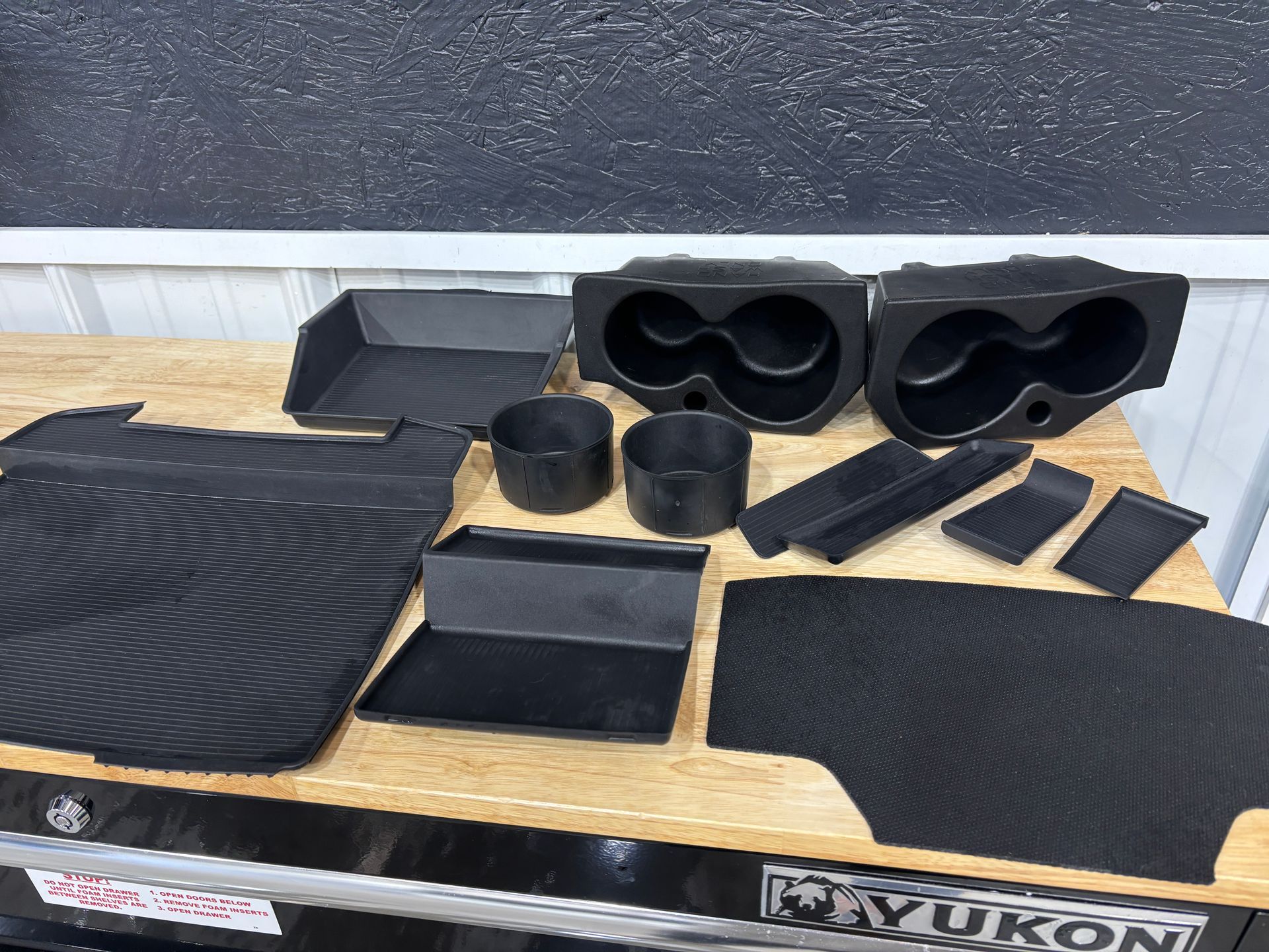 Black plastic car interior accessory set on a workbench.