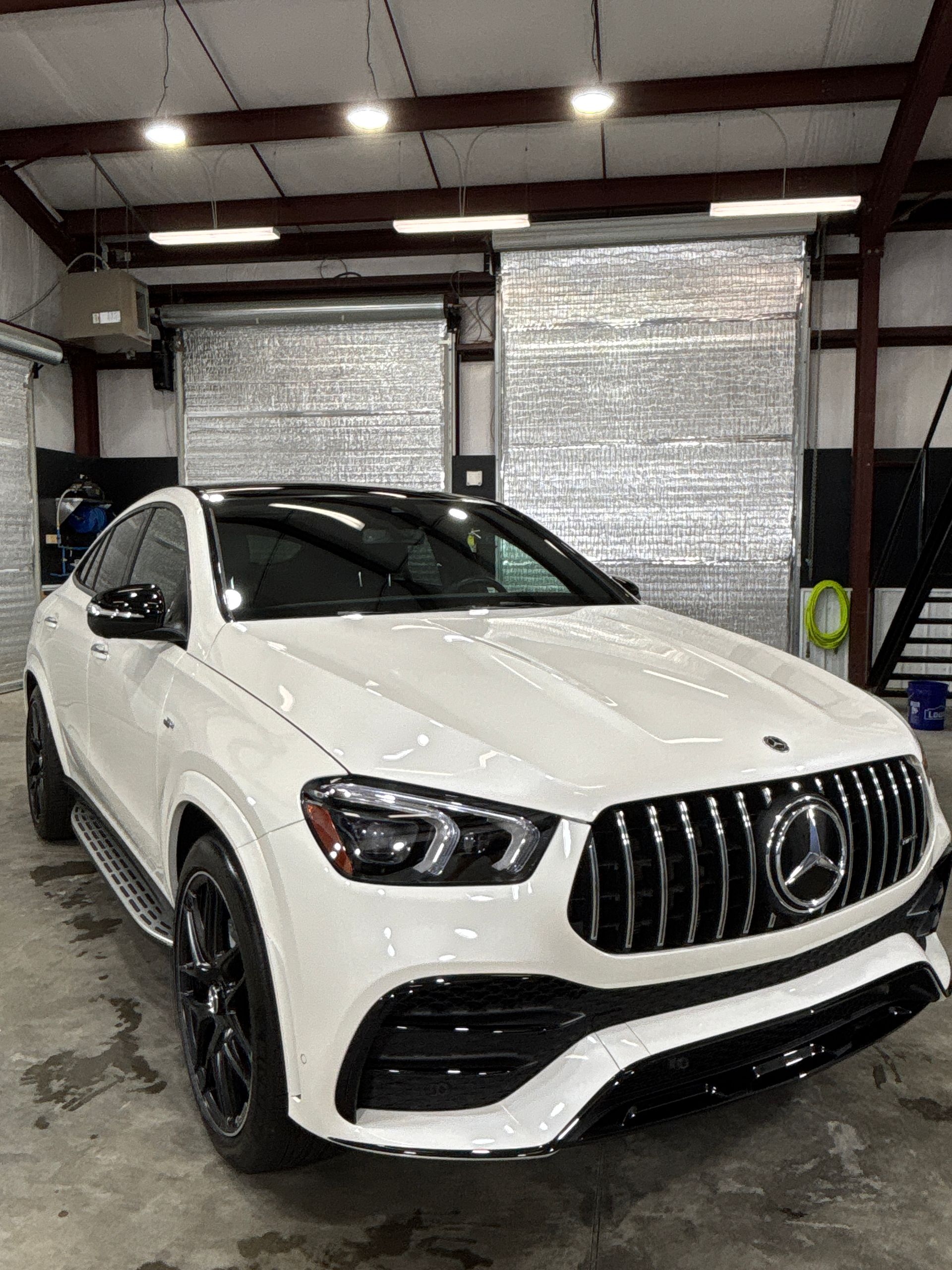White Mercedes-AMG GLE SUV parked inside a garage. The front grill is black and the roof is also black.
