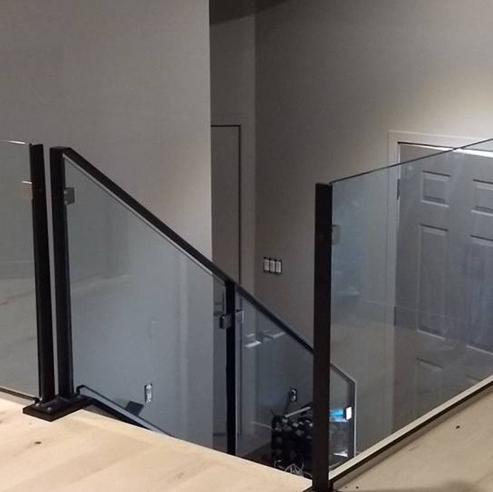 Glass and black metal railing on a landing, leading to a door and lower level.