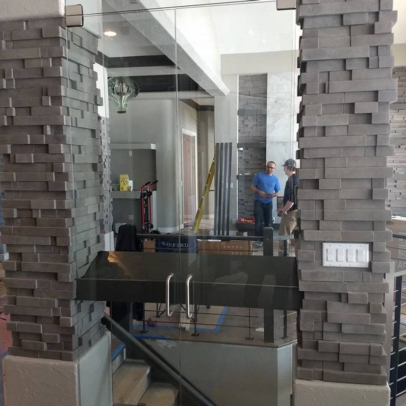 Glass door with stone pillars and two men in background.