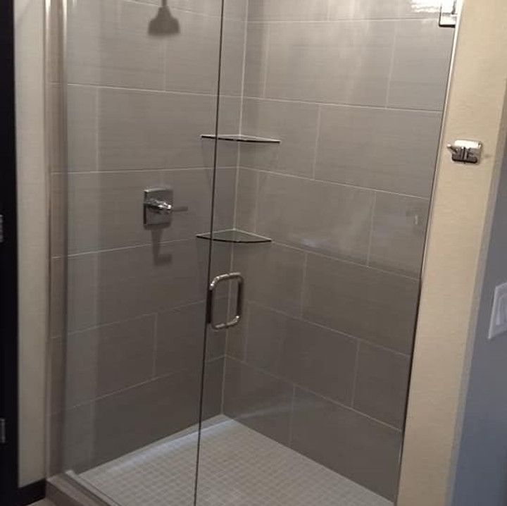 Gray tiled shower with glass door and silver fixtures.