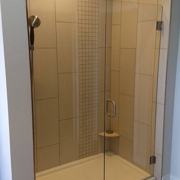 Glass-door shower with beige and gray tile walls, and a white shower pan.