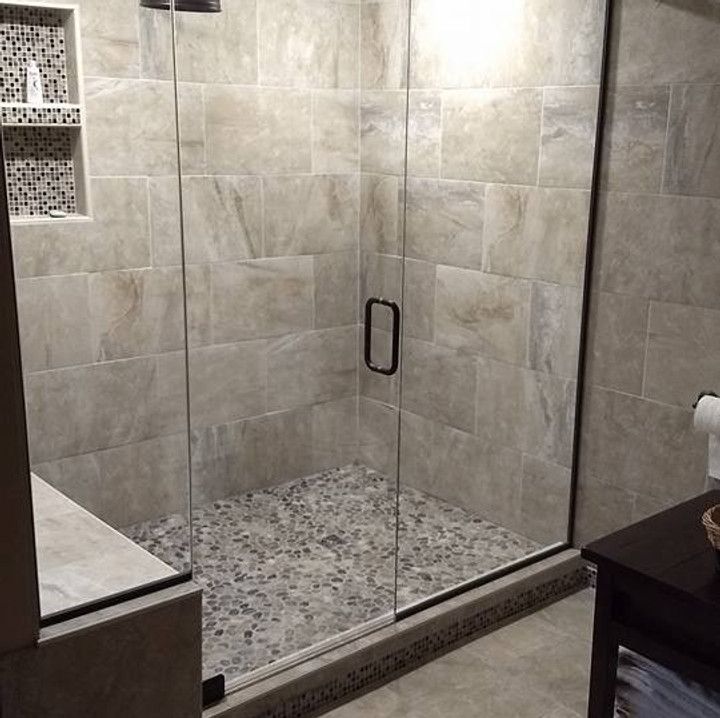 Shower stall with pebble floor and glass doors, tiled walls.