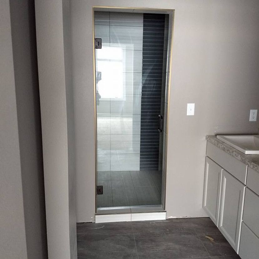 Bathroom with glass shower door, light gray walls, white cabinets, and dark gray floor tile.
