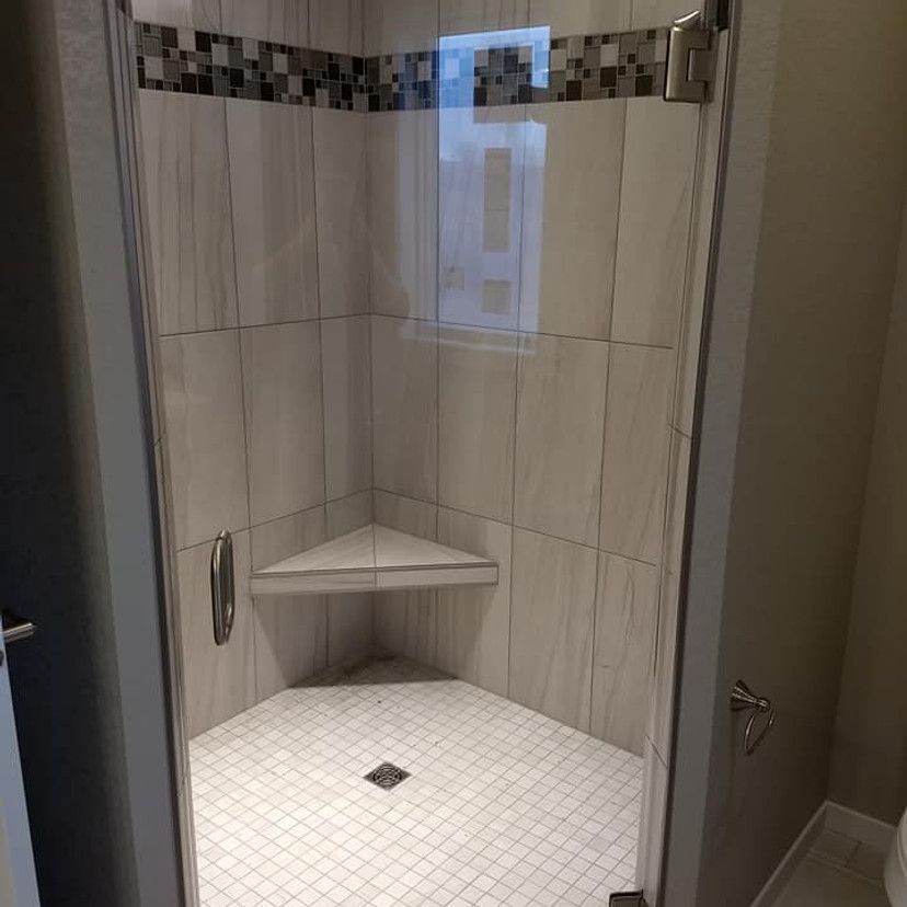 Corner shower with glass doors, white tile, and a built-in triangular bench.