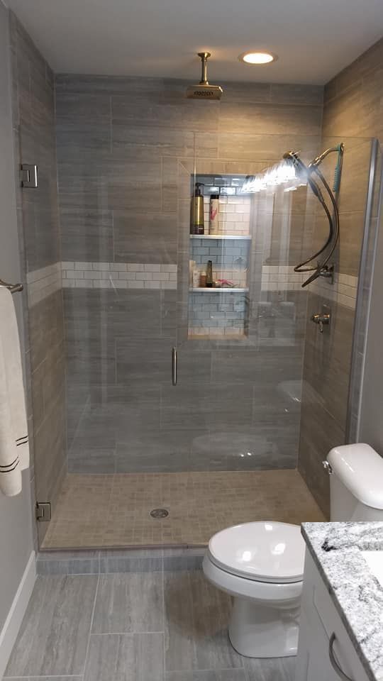 Modern bathroom with a glass shower, tiled walls, and a toilet.