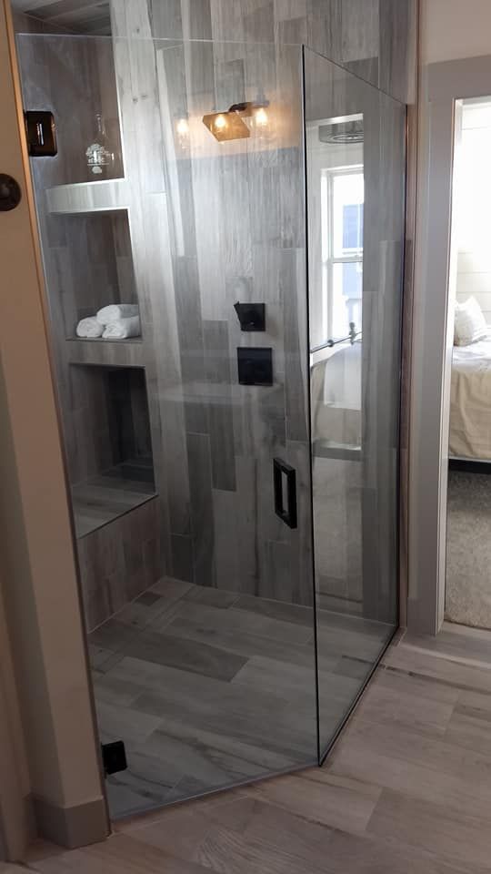 Modern shower with glass door and gray wood-look tile, with built-in shelves.
