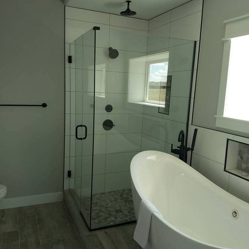 Modern bathroom with a glass shower enclosure, a bathtub, and white and gray tiles.
